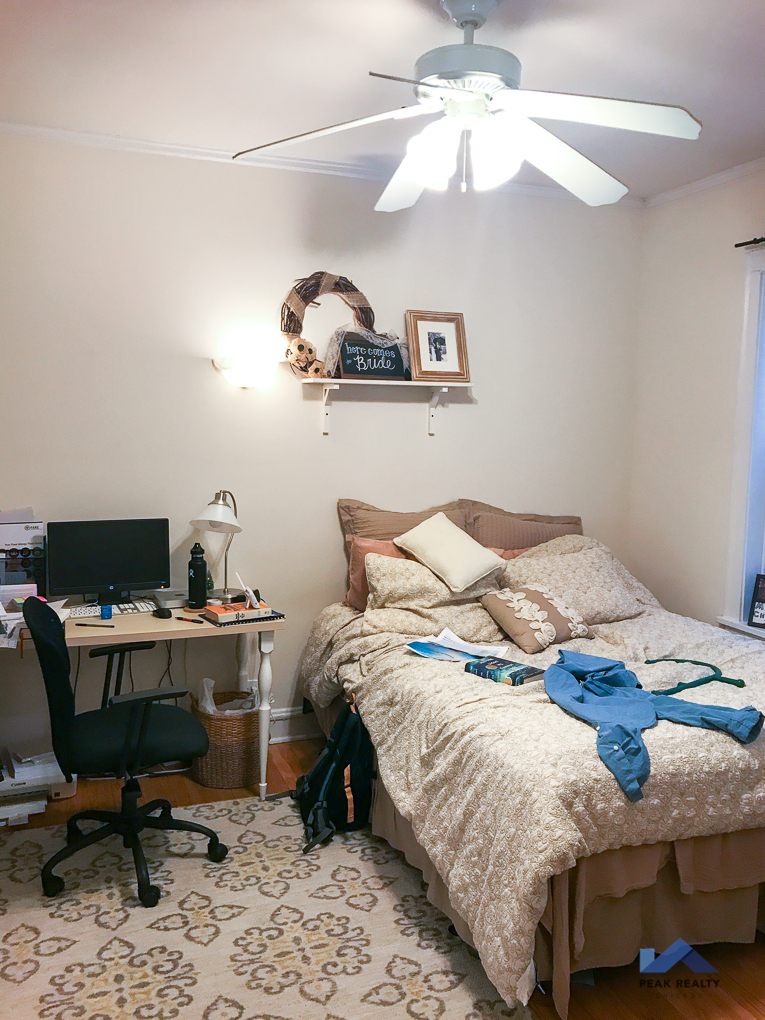 a bedroom with a bed and a desk and a ceiling fan
